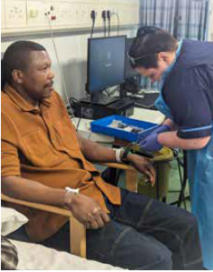 Man sitting with a nurse as he receives the first cancer vaccine.