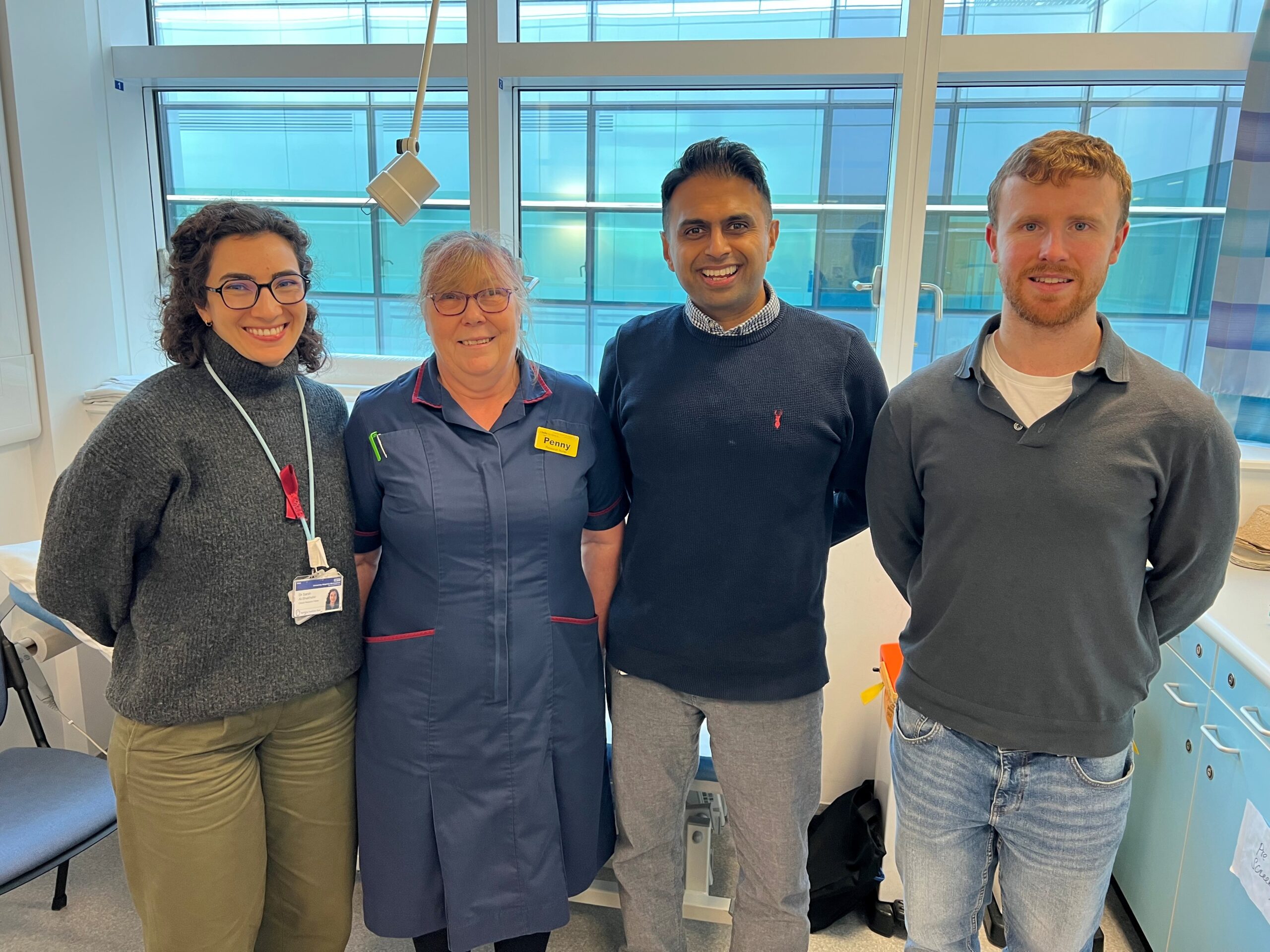 Photograph of four people standing in a clinic room. Two females and two males.
