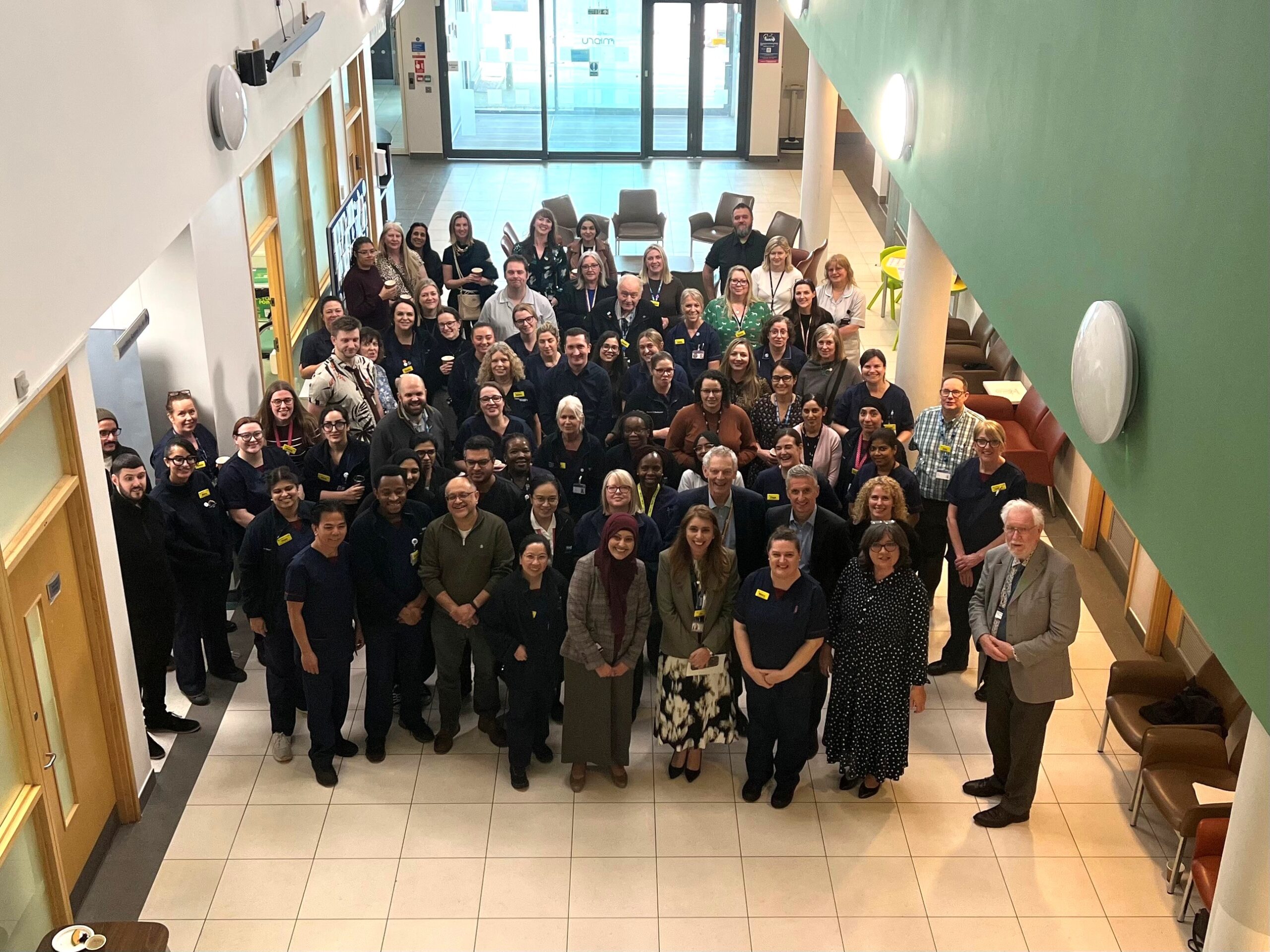 A large group of people standing together for a photograph in a hospital waiting area.