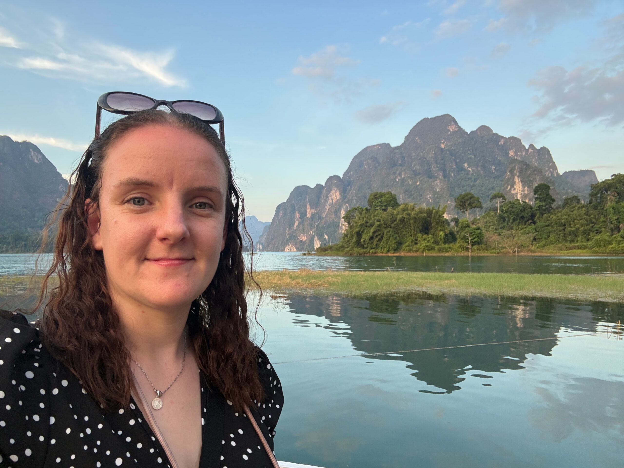 Head and shoulders shot of a female standing outdoors, in front of a reflective lake.