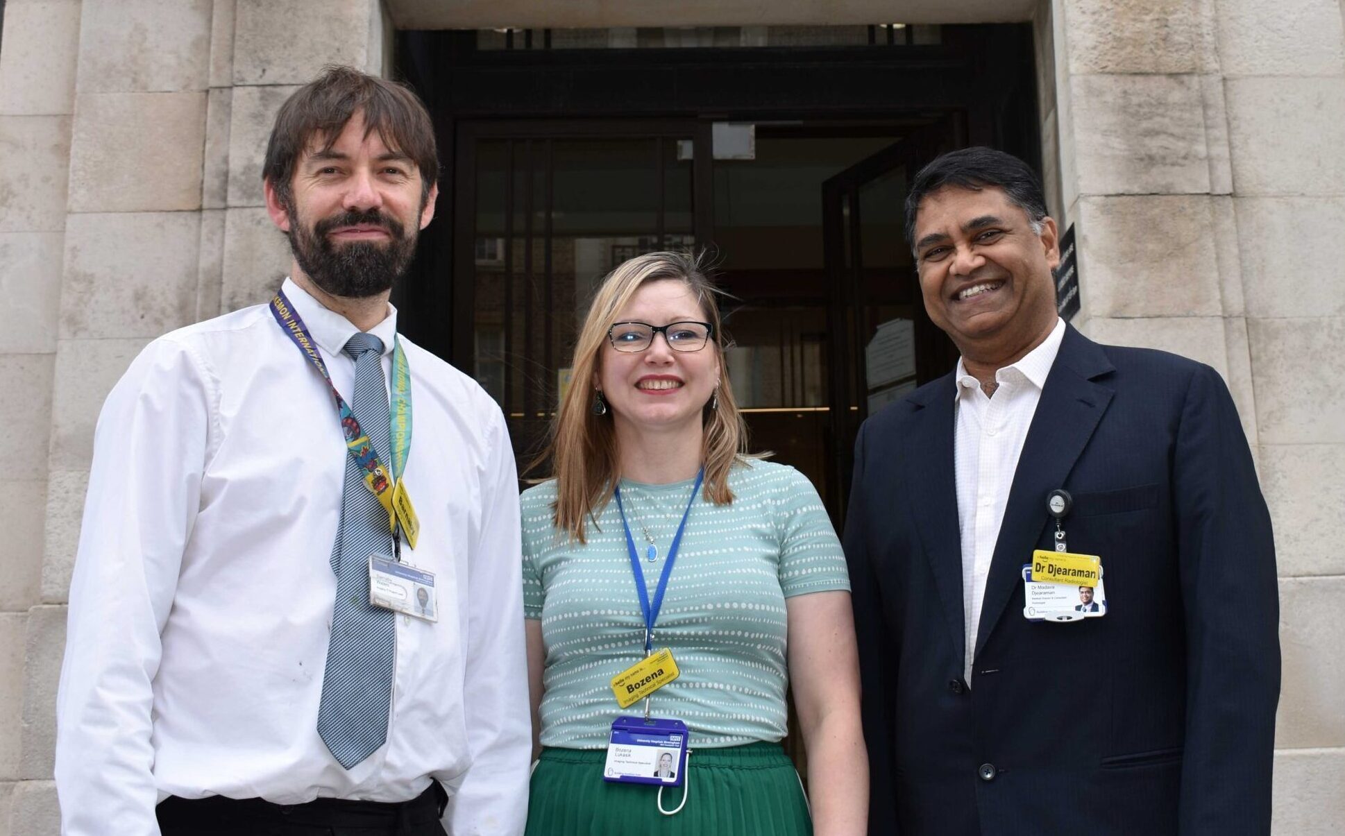 Three people standing in front of a building smiling